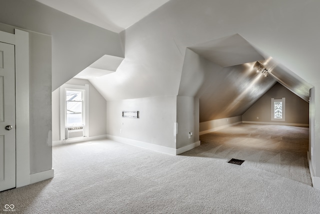 bonus room with light carpet and vaulted ceiling