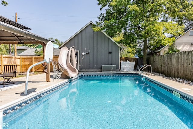 view of pool with a water slide, a shed, and a patio