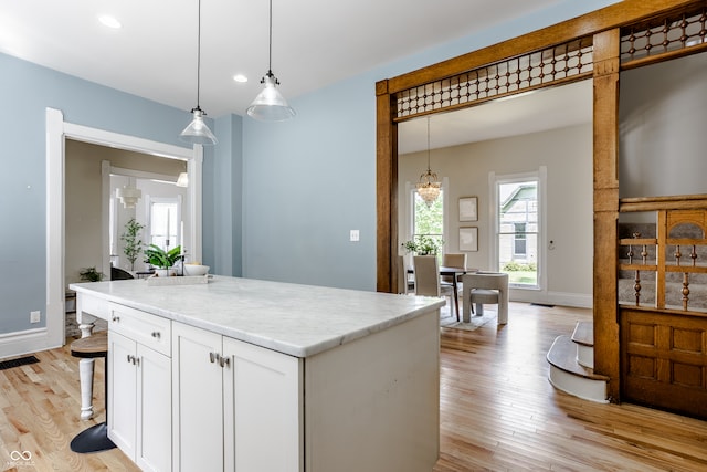 kitchen featuring a kitchen island, pendant lighting, white cabinetry, and light hardwood / wood-style floors