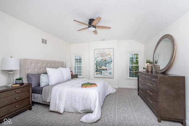 carpeted bedroom with a textured ceiling, vaulted ceiling, and ceiling fan