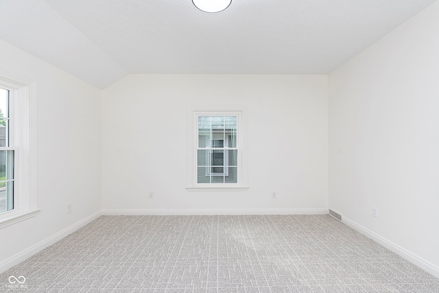 carpeted spare room with vaulted ceiling