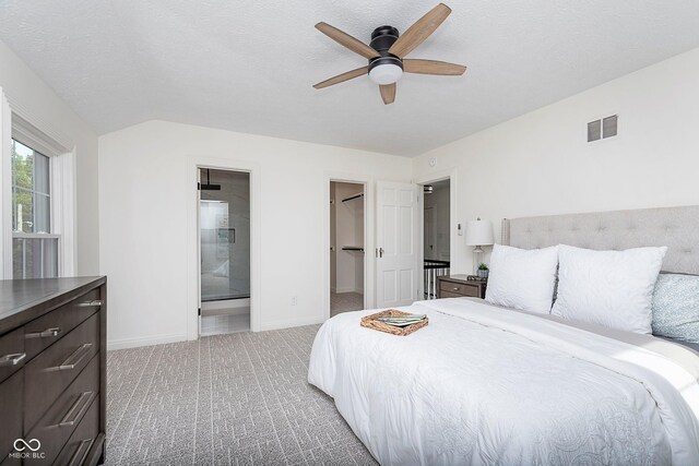 bedroom featuring a walk in closet, ensuite bath, carpet, and ceiling fan