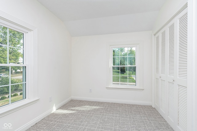 unfurnished bedroom featuring multiple windows, a closet, carpet flooring, and vaulted ceiling