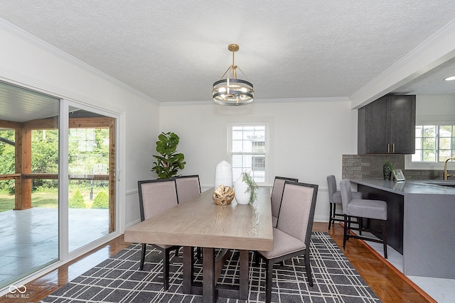 dining area featuring crown molding, a textured ceiling, a chandelier, and sink