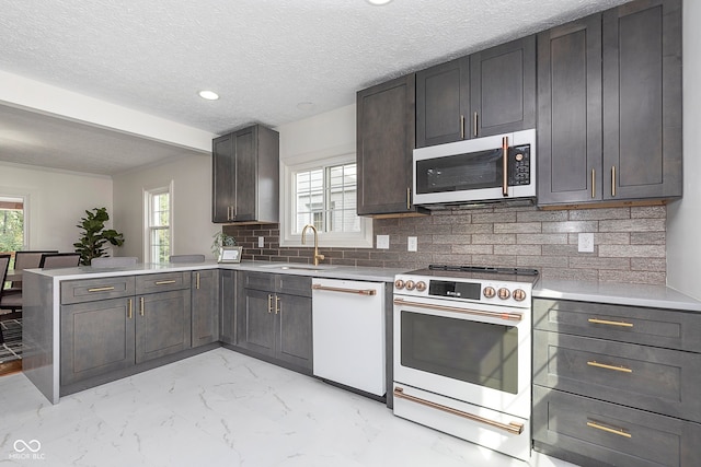 kitchen featuring kitchen peninsula, sink, a textured ceiling, white appliances, and tasteful backsplash