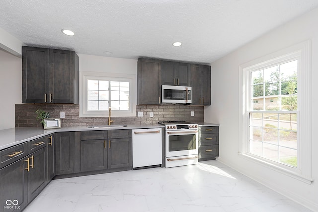 kitchen with white appliances, backsplash, dark brown cabinetry, and sink