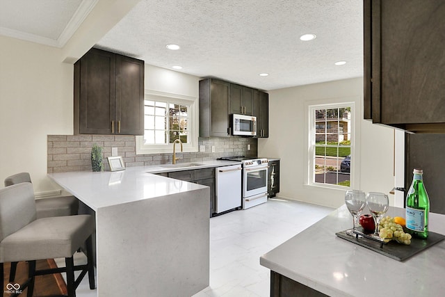 22 W 54th St, Indianapolis, IN 46208 - kitchen with a sink, a breakfast bar, dark brown cabinetry, white appliances, and a peninsula