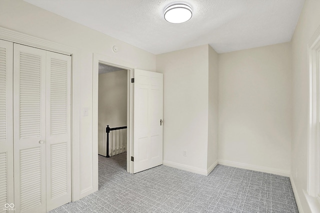 22 W 54th St, Indianapolis, IN 46208 - unfurnished bedroom featuring a textured ceiling, light colored carpet, baseboards, and a closet