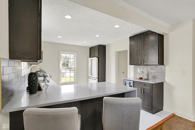 22 W 54th St, Indianapolis, IN 46208 - kitchen with high end fridge, light countertops, dark brown cabinets, backsplash, and a peninsula