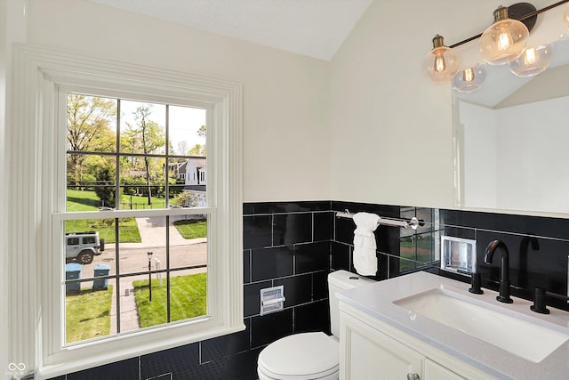 22 W 54th St, Indianapolis, IN 46208 - bathroom with tile walls, toilet, lofted ceiling, and vanity
