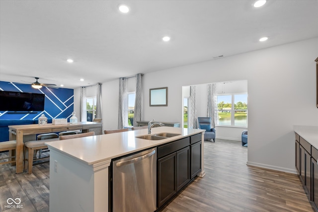 kitchen featuring dark wood-type flooring, an island with sink, dark brown cabinetry, stainless steel dishwasher, and sink