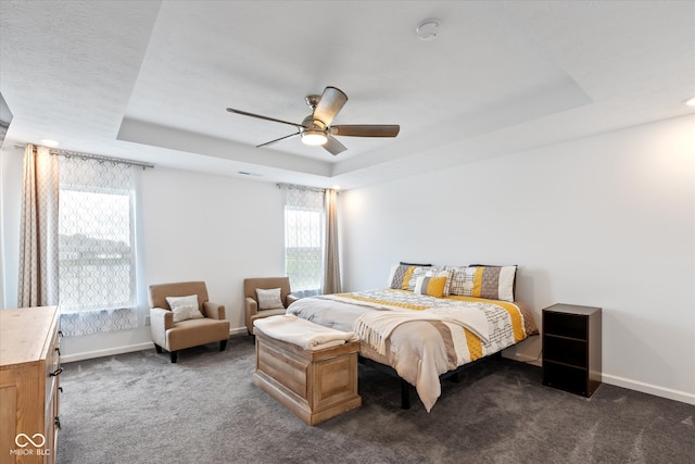 carpeted bedroom with ceiling fan and a raised ceiling