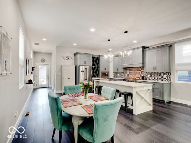 dining area featuring an inviting chandelier, sink, and dark hardwood / wood-style flooring