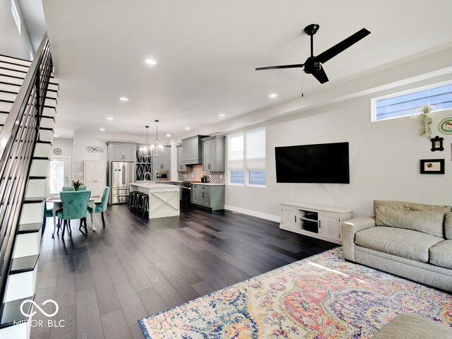 living room featuring ceiling fan with notable chandelier, a wealth of natural light, dark hardwood / wood-style floors, and sink