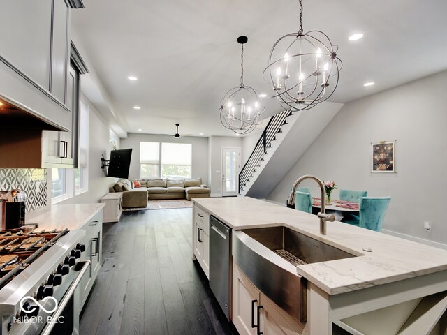 kitchen with dark hardwood / wood-style floors, hanging light fixtures, stainless steel appliances, sink, and light stone counters