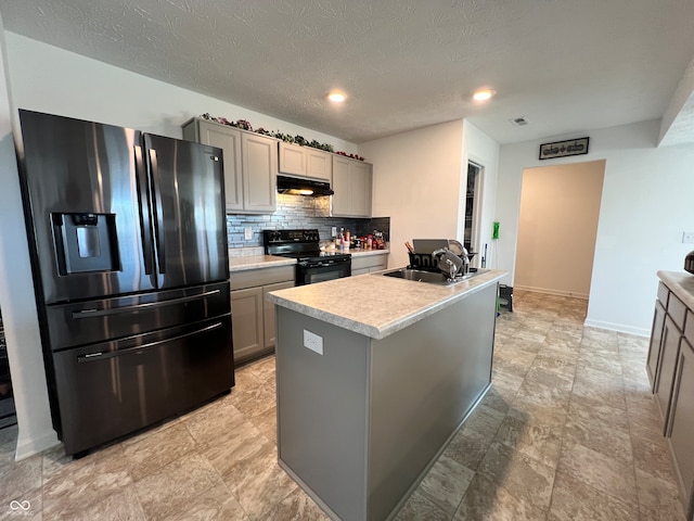 kitchen featuring a kitchen island with sink, stainless steel fridge, gray cabinets, and electric range