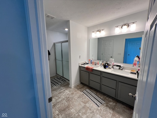 bathroom with vanity, a textured ceiling, and a shower with shower door