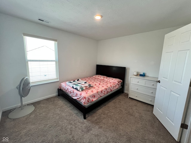 bedroom featuring a textured ceiling and dark carpet