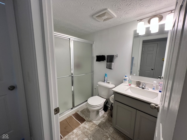 bathroom featuring vanity, toilet, a textured ceiling, and a shower with door