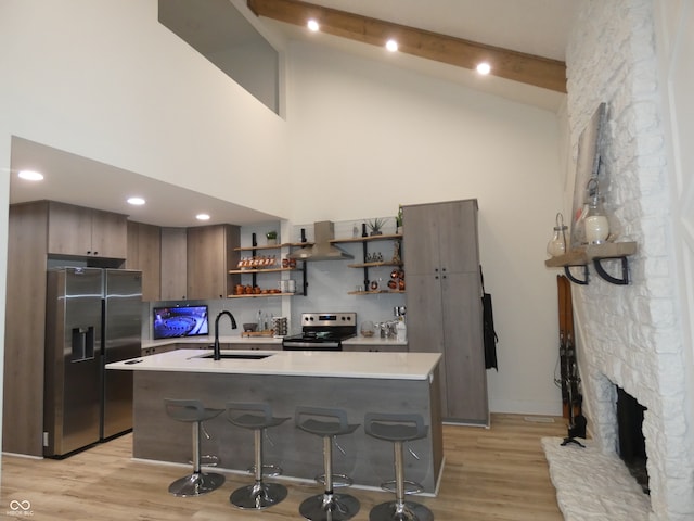 kitchen featuring stainless steel appliances, light hardwood / wood-style floors, sink, extractor fan, and a kitchen bar