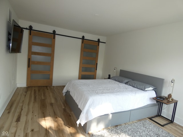 bedroom with hardwood / wood-style flooring and a barn door