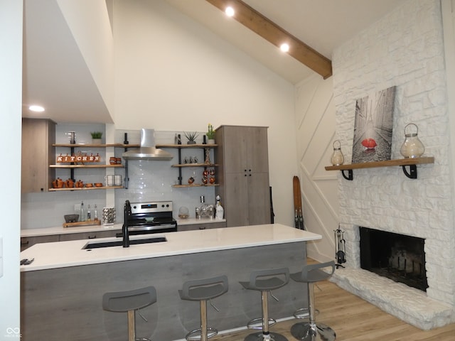 bar featuring lofted ceiling with beams, a stone fireplace, sink, ventilation hood, and stainless steel range with electric stovetop