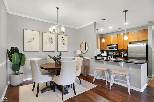 dining room featuring sink, dark hardwood / wood-style floors, a chandelier, and crown molding