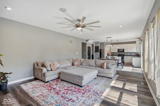 living room featuring dark wood-type flooring and ceiling fan