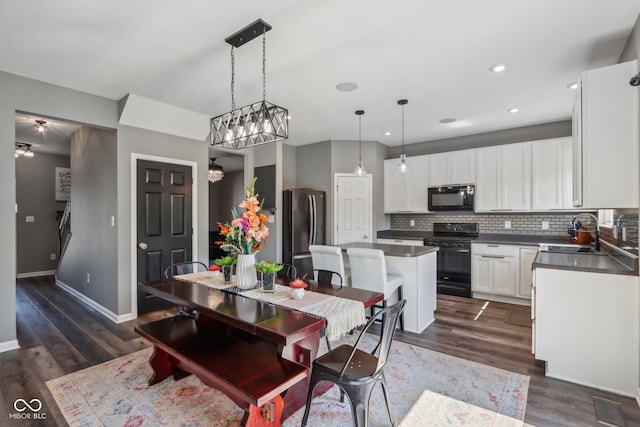 dining room with dark wood-type flooring, an inviting chandelier, and sink