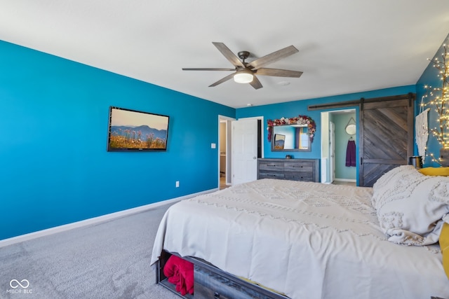 bedroom with ceiling fan, a barn door, and carpet