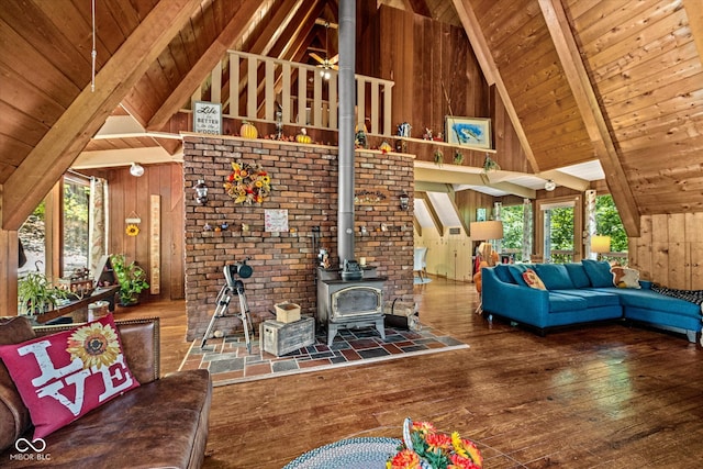 unfurnished living room with high vaulted ceiling, beamed ceiling, a wood stove, and hardwood / wood-style flooring