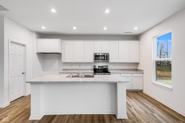 kitchen with sink, white cabinetry, stainless steel appliances, and a kitchen island with sink