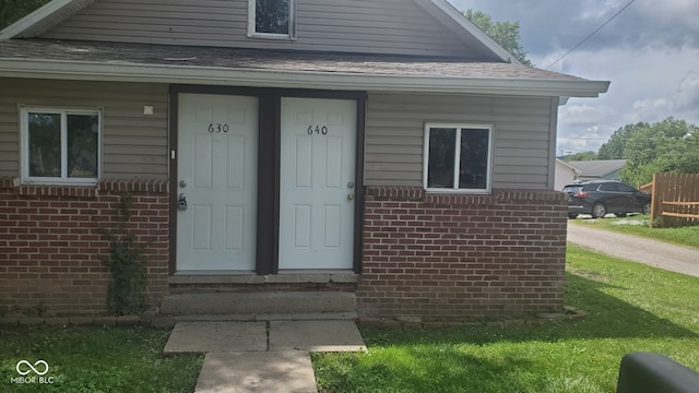 view of exterior entry featuring a lawn