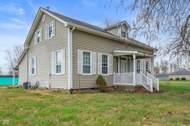 view of front of home featuring a front lawn, central air condition unit, and covered porch