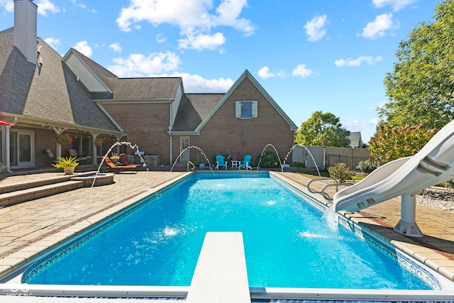 view of pool featuring a diving board, fence, a fenced in pool, a water slide, and a patio area