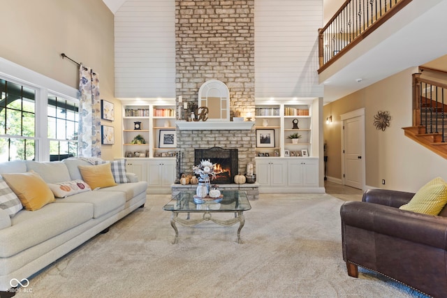 living area featuring carpet flooring, a fireplace, high vaulted ceiling, built in features, and stairs