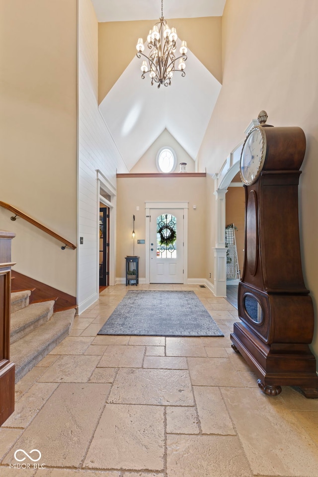 entrance foyer featuring high vaulted ceiling, a notable chandelier, stone tile flooring, and stairway