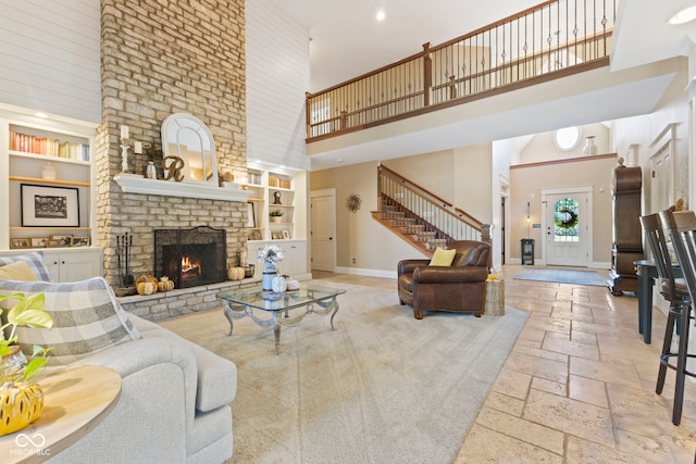 living room with a towering ceiling, built in features, and a brick fireplace