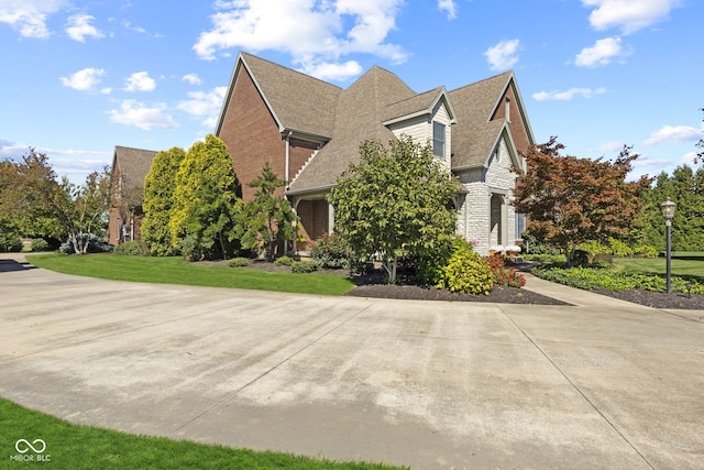 view of home's exterior featuring a lawn, brick siding, and roof with shingles