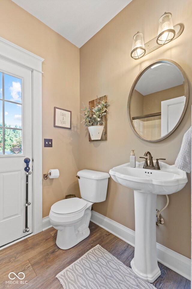 bathroom featuring toilet, wood finished floors, and baseboards
