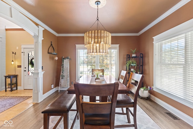 dining room with decorative columns, light hardwood / wood-style floors, crown molding, and a notable chandelier