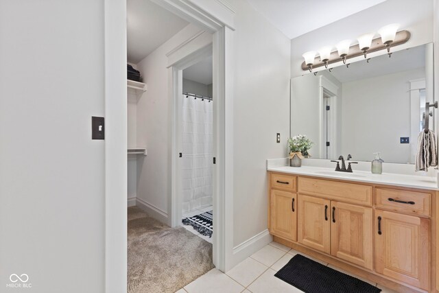 bathroom featuring curtained shower, vanity, tile patterned flooring, and baseboards