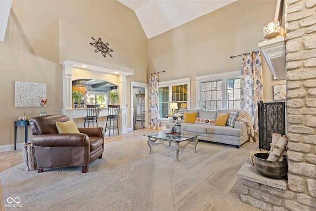 living room with high vaulted ceiling, decorative columns, light carpet, and a wealth of natural light