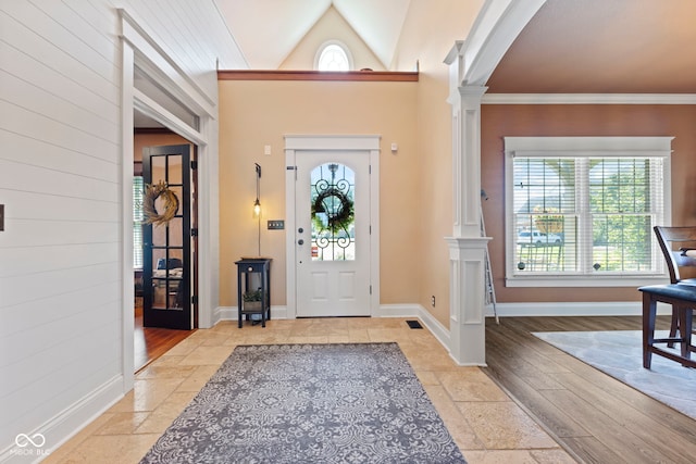 entryway with a healthy amount of sunlight, ornamental molding, vaulted ceiling, and ornate columns