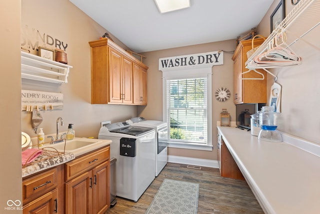 washroom with baseboards, cabinet space, a sink, dark wood-style floors, and washing machine and dryer