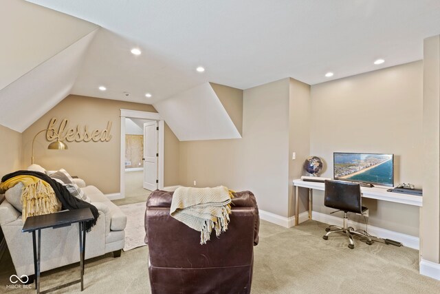 interior space with built in desk, vaulted ceiling, and light carpet