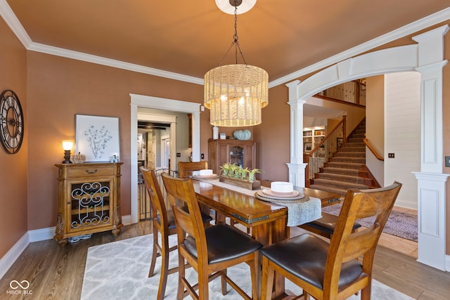 dining room with crown molding, stairway, a chandelier, decorative columns, and wood finished floors