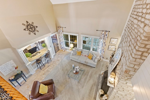 living room with decorative columns, a fireplace, and a towering ceiling