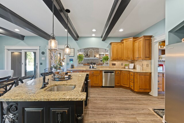 kitchen featuring beamed ceiling, a sink, light wood-style flooring, backsplash, and appliances with stainless steel finishes