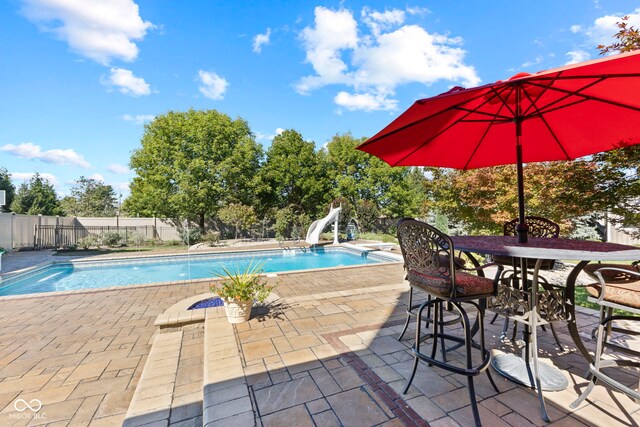 view of pool featuring a patio area, a diving board, a fenced in pool, a fenced backyard, and a water slide